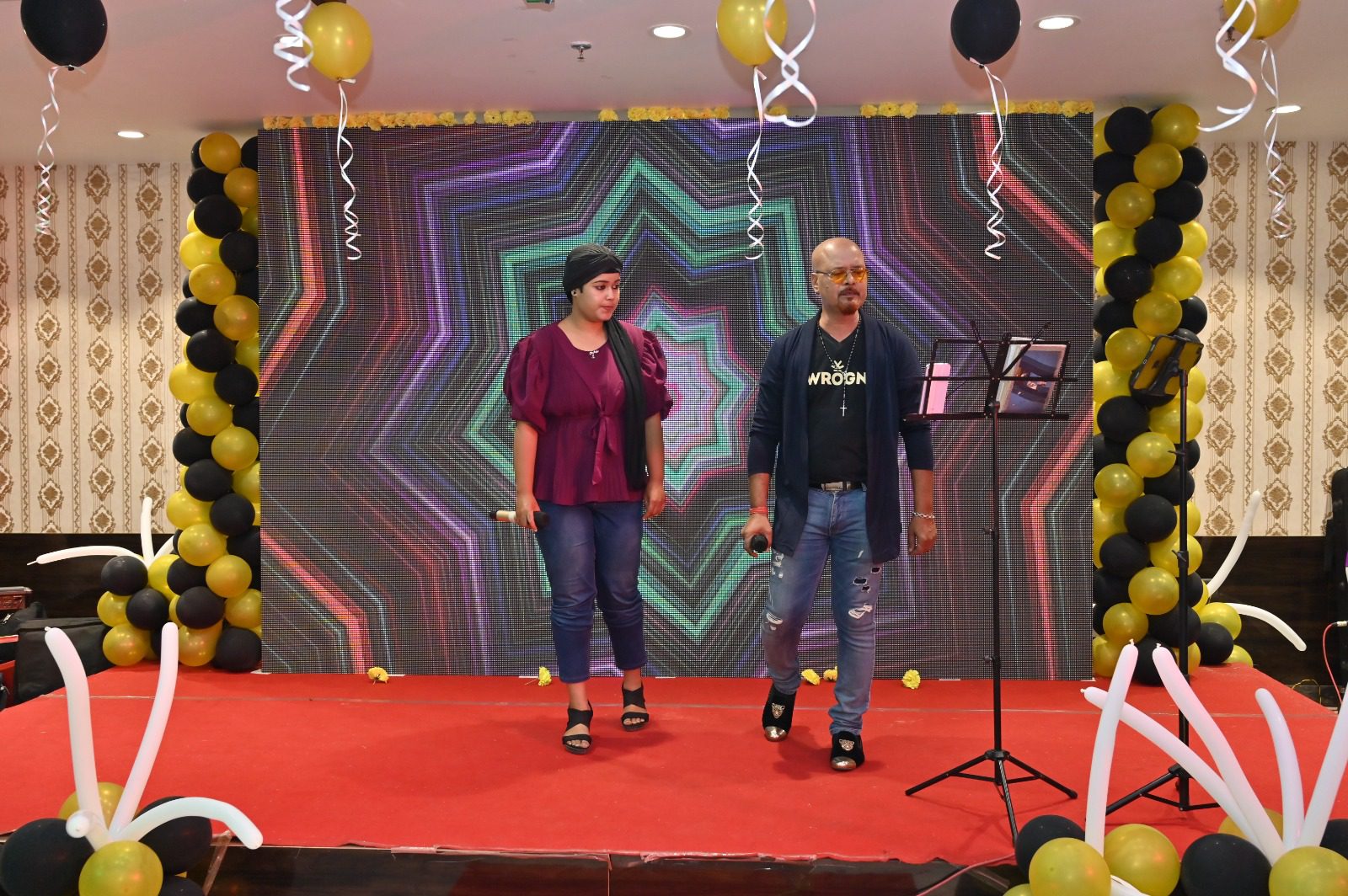 A man and a girl standing on stage with a mic